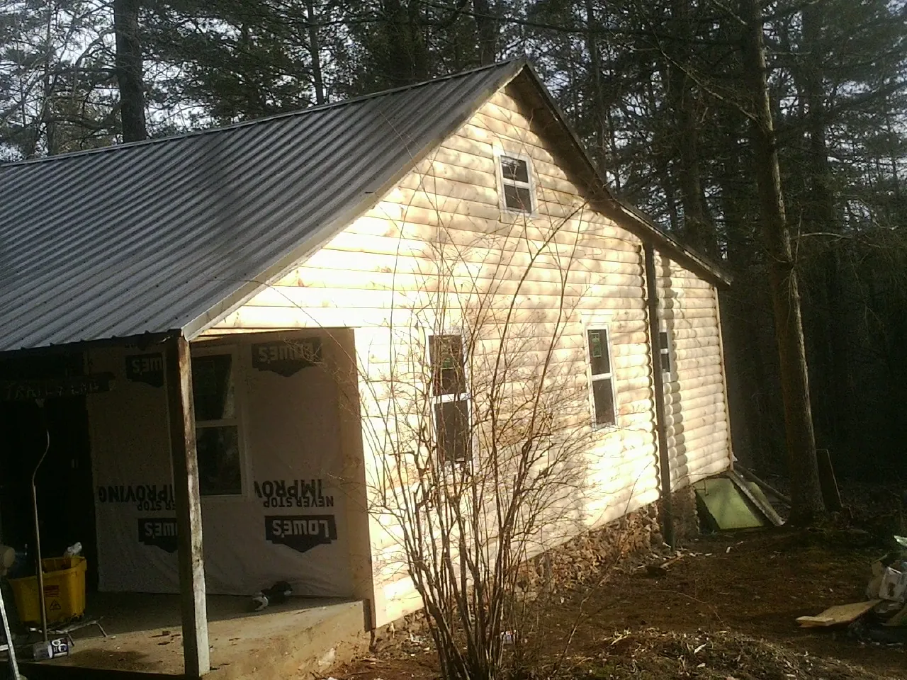 Log siding gable end under a dark metal roof edge in Eden