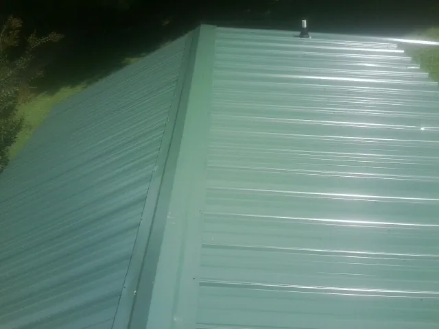New green metal panels meeting at the ridge of a roof — Flat Roof Repair work by our crew in Eden