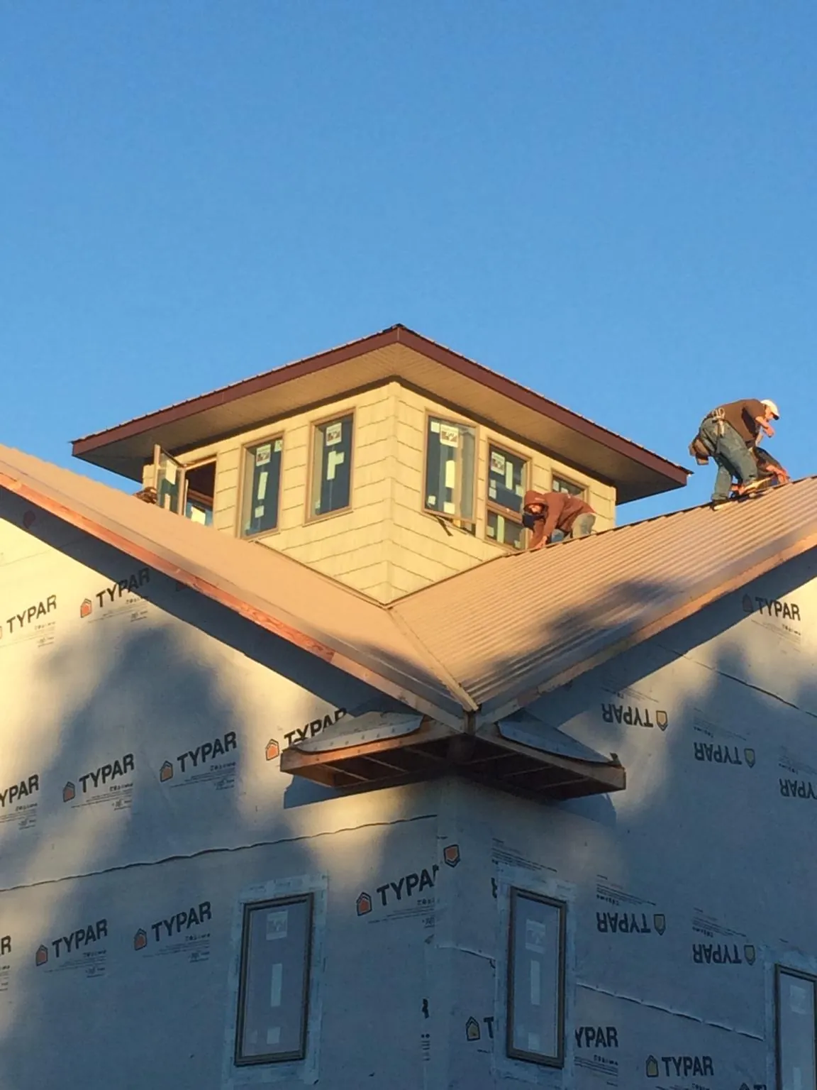 Roofers working around a rooftop cupola on a new metal roof at sunset — Roof Waterproofing in Eden by Roofing Brothers